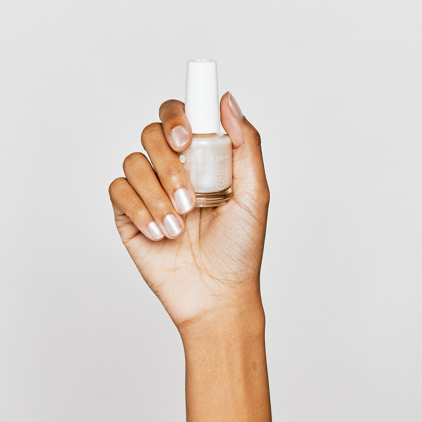Hand with Pearl painted on nails holding lacquer bottle