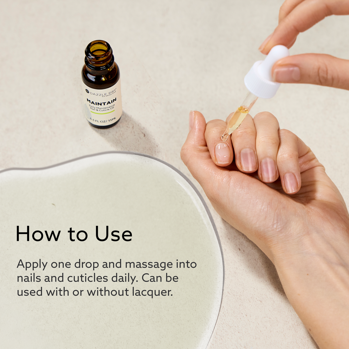 Hand applying Dazzle Dry MAINTAIN Daily Maintenance Nail & Cuticle Oil to nails using a dropper, with usage instructions shown on a neutral background