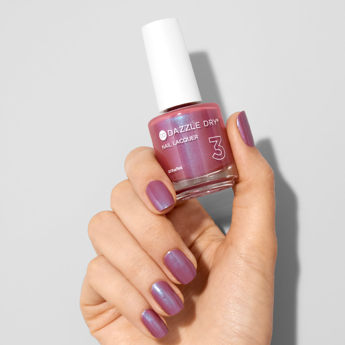 Hand with School Spirit painted on nails holding lacquer bottle