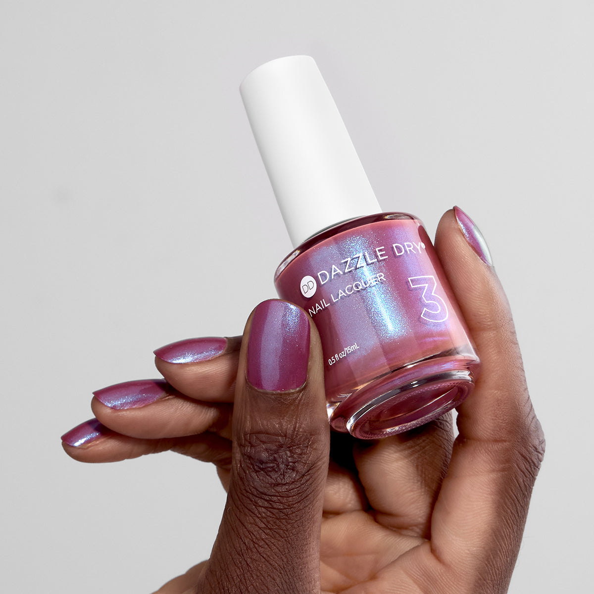 Hand with School Spirit painted on nails holding lacquer bottle