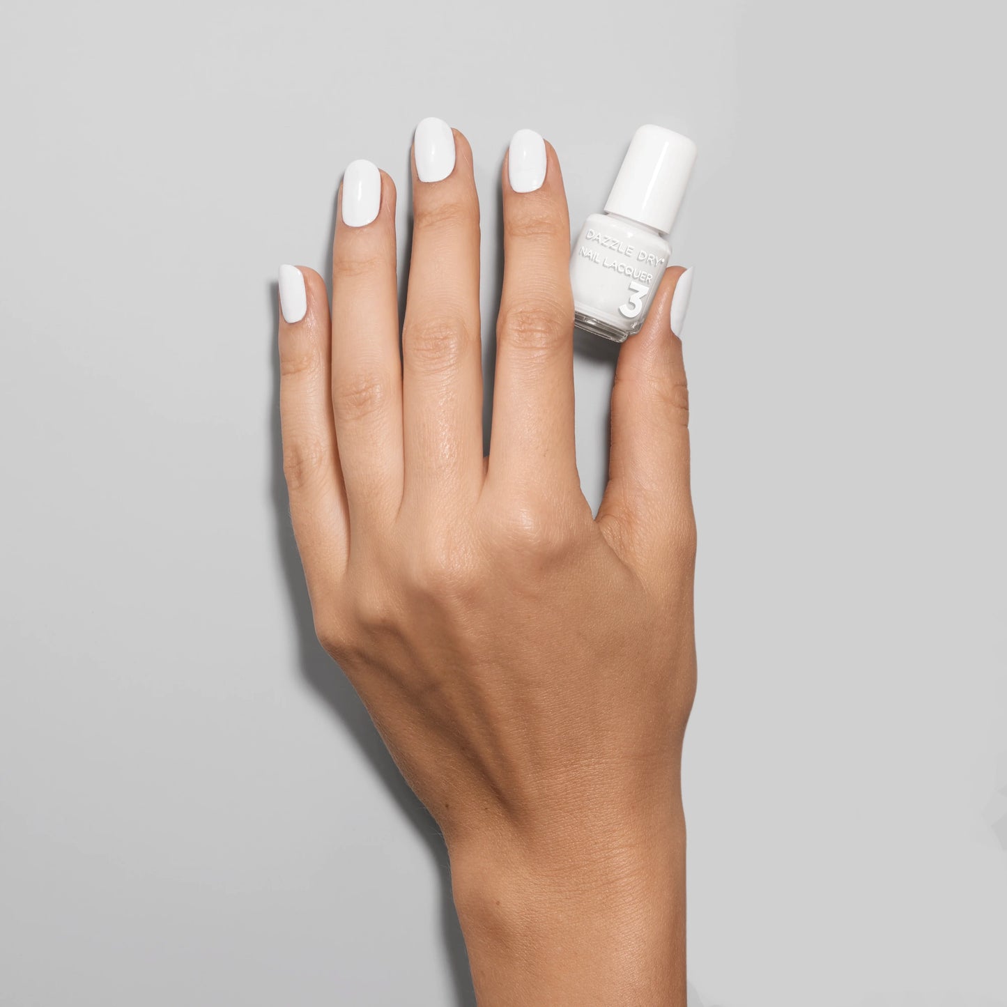 Hand with White Lightning painted on nails holding mini nail lacquer bottle