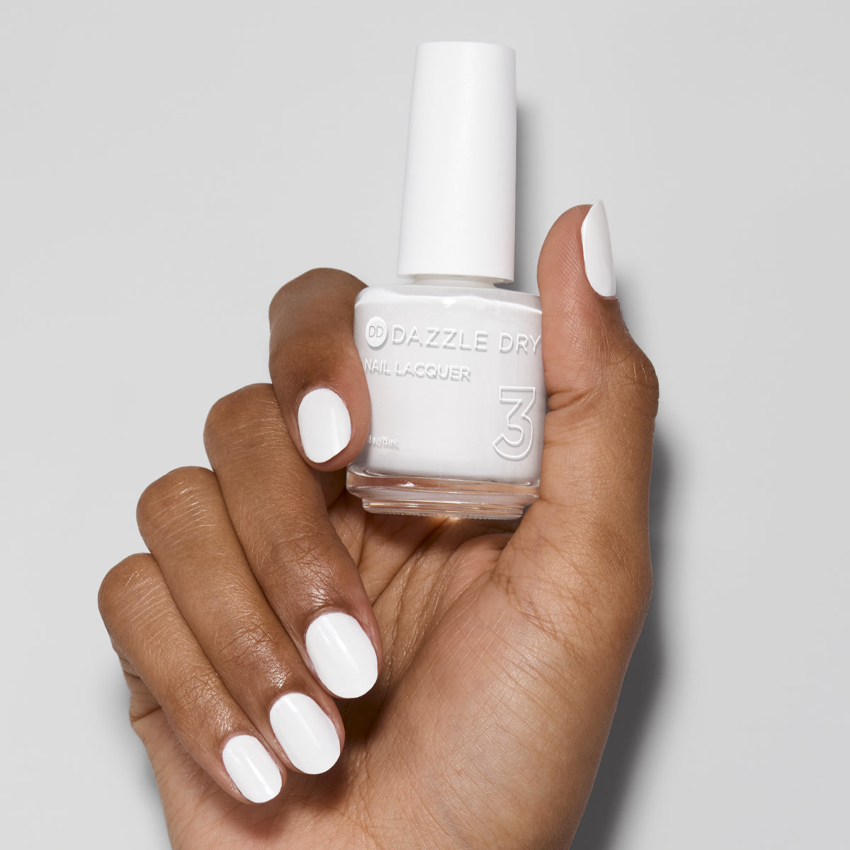 Hand with White Lightning painted on nails holding lacquer bottle