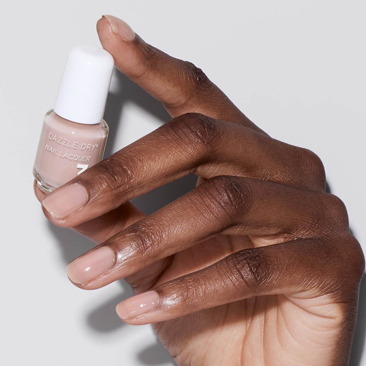 Hand with Chiffon Moment painted on nails holding mini nail lacquer bottle
