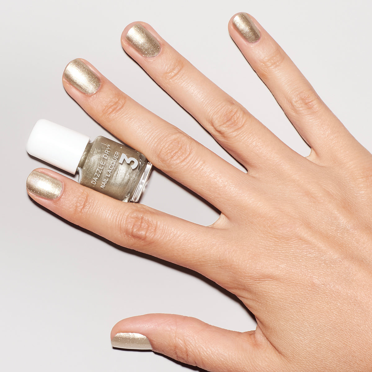 Hand with Illuminate painted on nails holding mini nail lacquer bottle