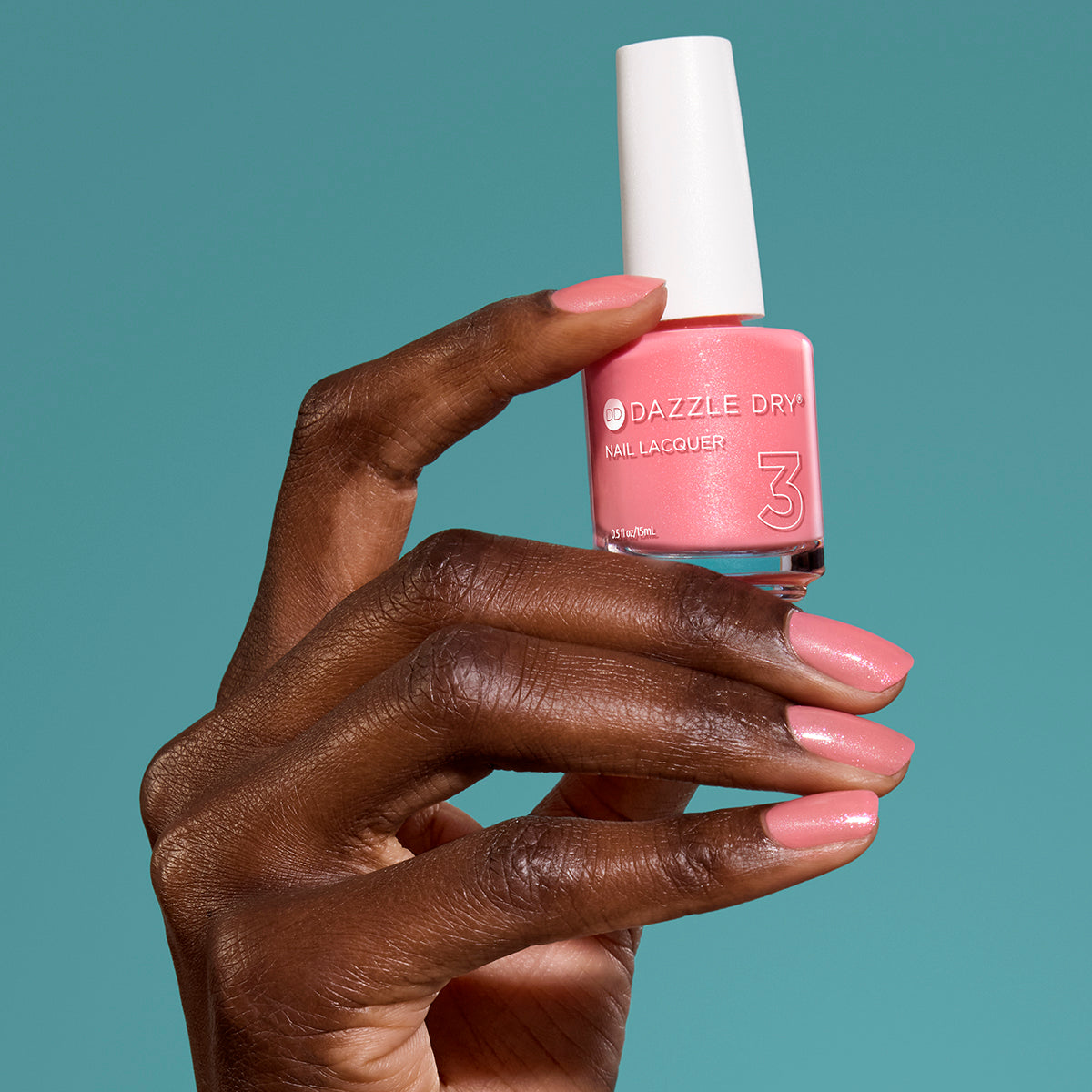 Hand with Cherry Blossom painted on nails holding full size lacquer bottle