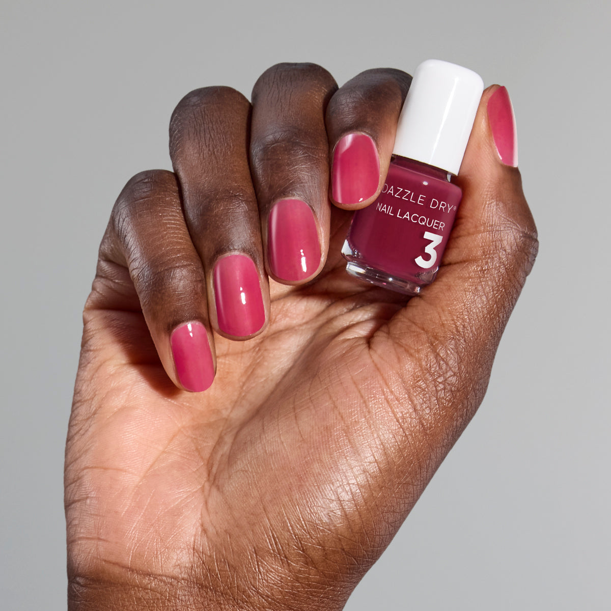 Hand with Ring Toss painted on nails holding mini nail lacquer bottle