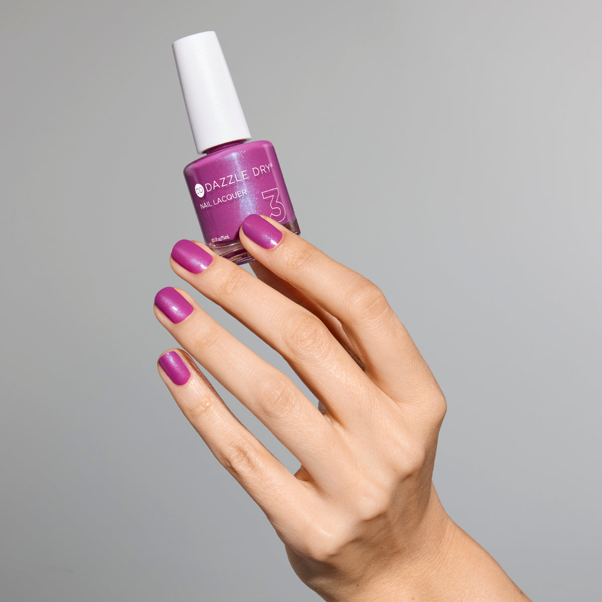 Hand with Mulberry painted on nails holding full size lacquer bottle