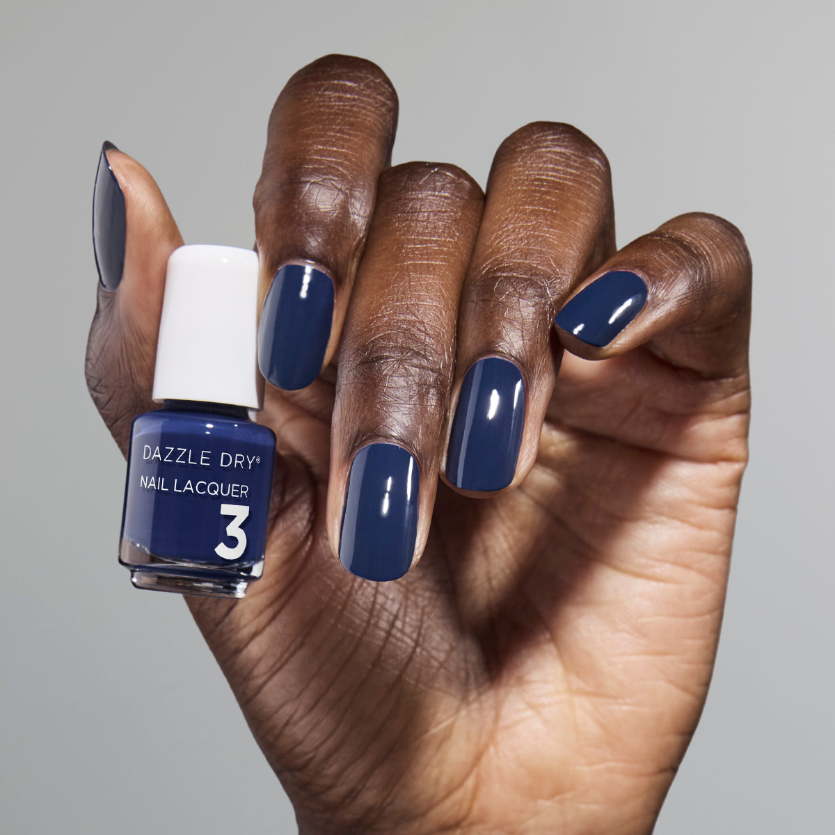 Hand with Midnight Sky painted on nails holding mini lacquer bottle