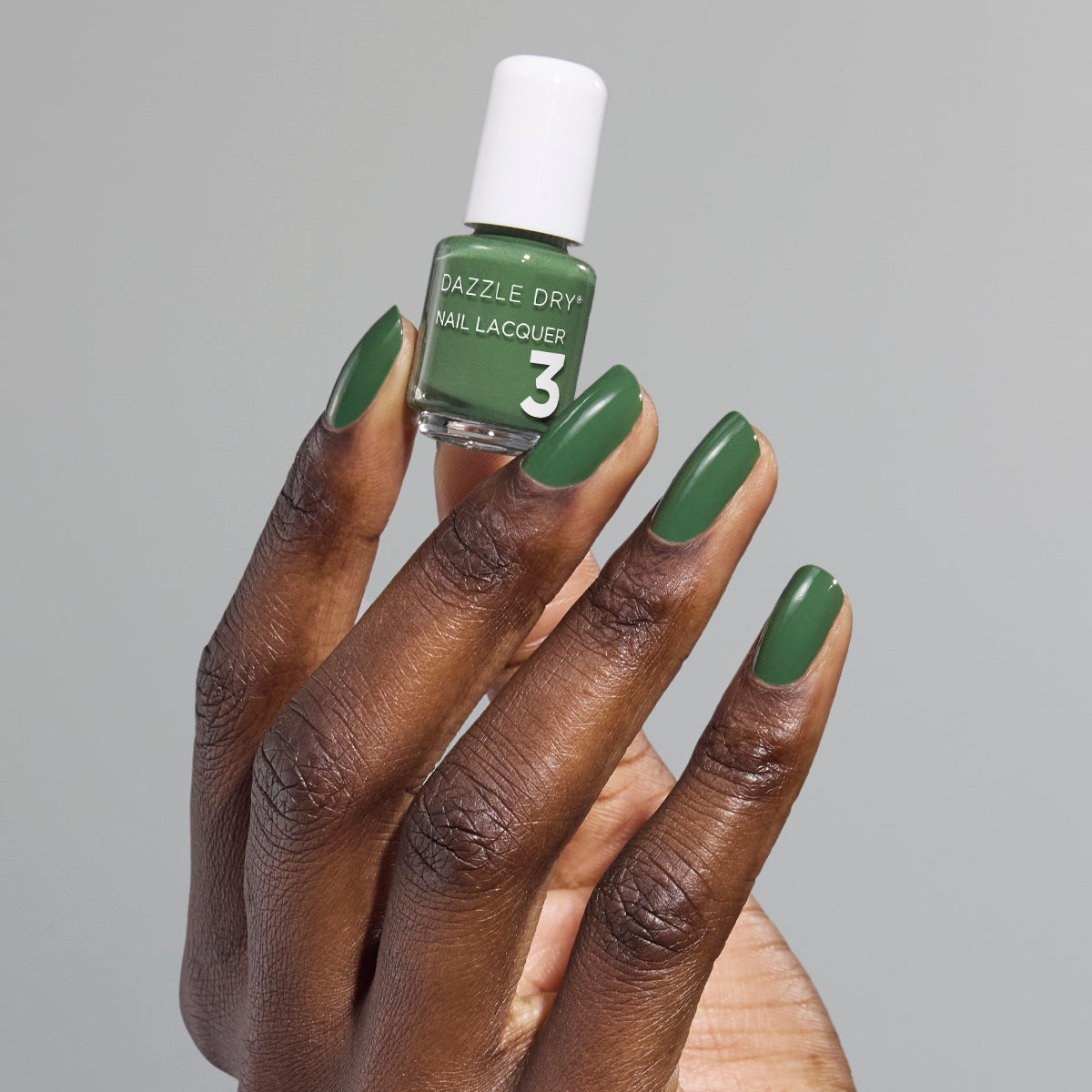 Hand with Fern painted on nails holding mini lacquer bottle