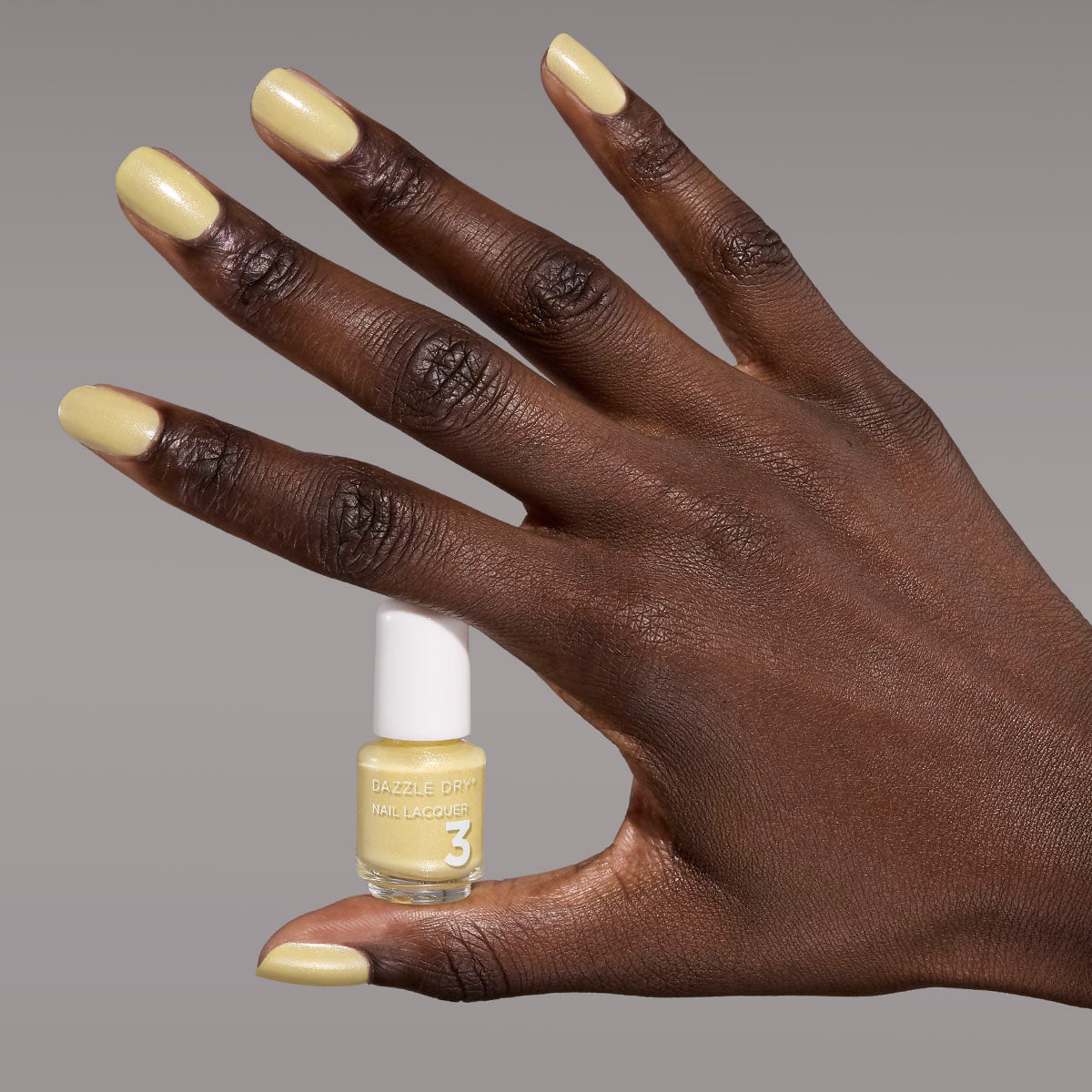 Hand with Solstice painted on nails holding mini lacquer bottle