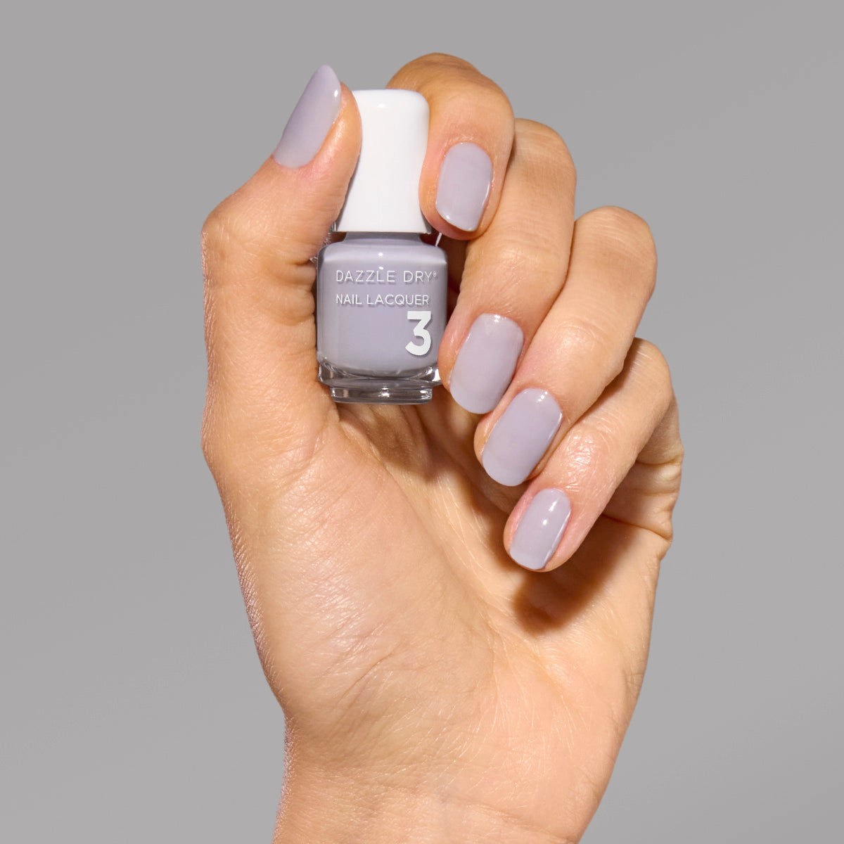 Hand with Fresh Start painted on nails holding mini nail lacquer bottle.