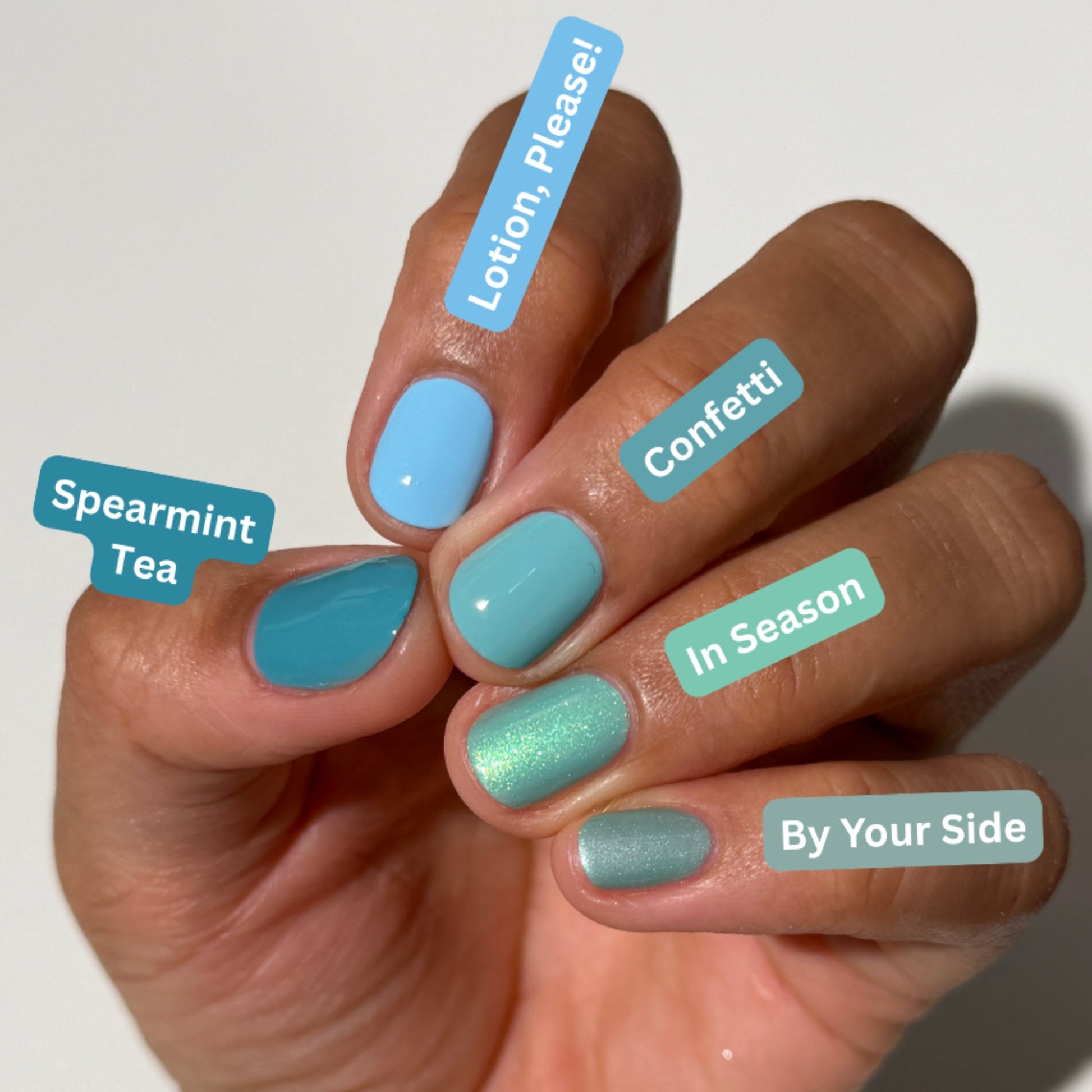 A close-up of a hand with six different pastel nail polish colors applied, each labeled with a text tag (Spearmint Tea, Lotion, Please!, Confetti, In Season, By Your Side). The nails are shown against a clean, light off-white background.