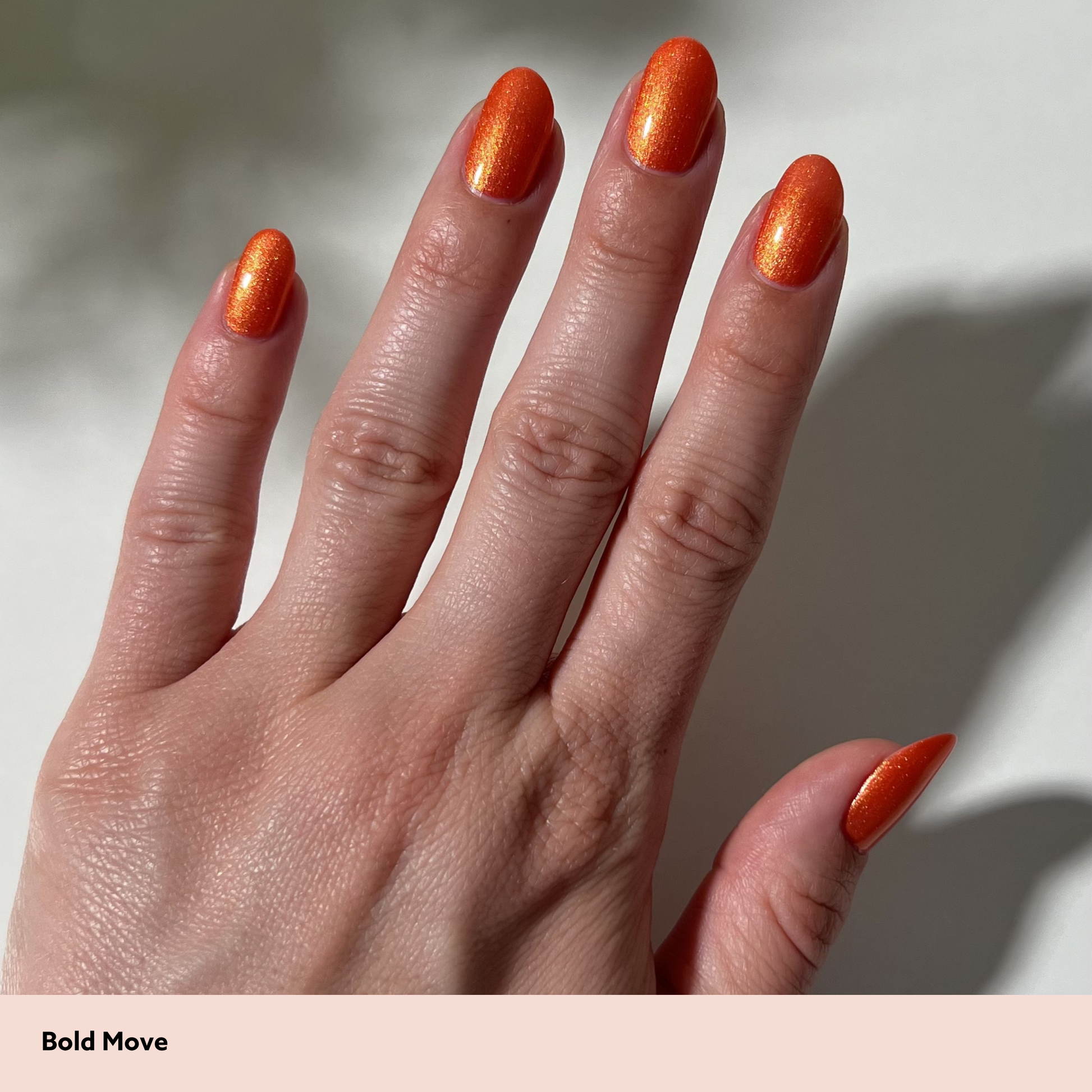 Hand with orange nail polish on a neutral background