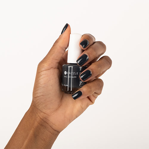 Hand with Joan's Armor painted on nails holding lacquer bottle