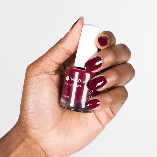 Hand with Red Rouge painted on nails holding lacquer bottle