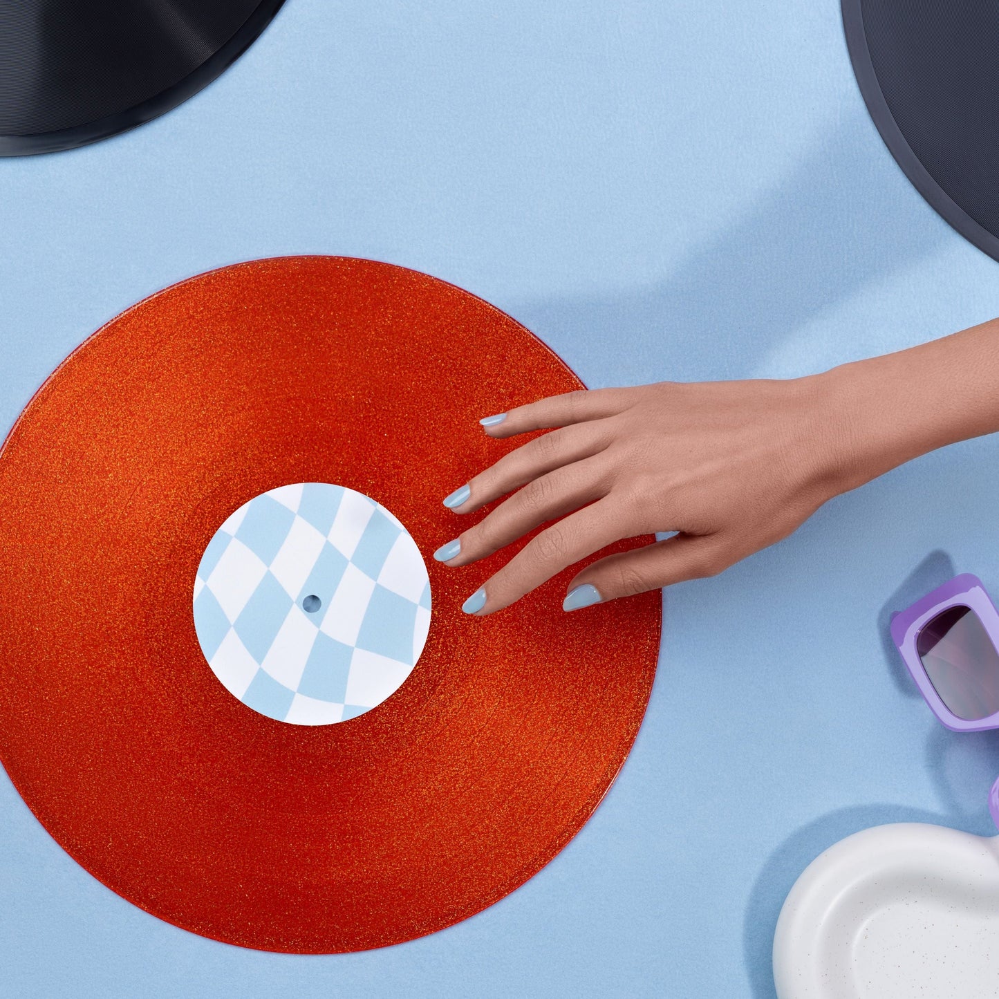 Person placing a red vinyl record with a blue and white label on a blue surface.