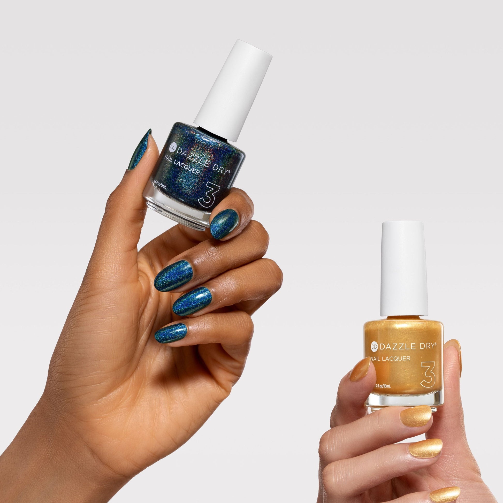 Two hands holding bottles of Dazzle City nail polish against a light gray background