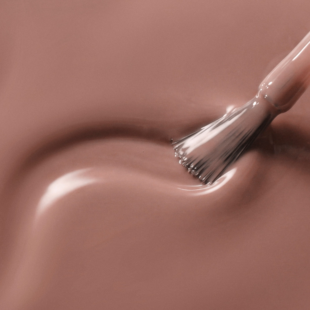 A close-up of a glossy mauve-pink liquid swatch with a brush stroke applying the color.