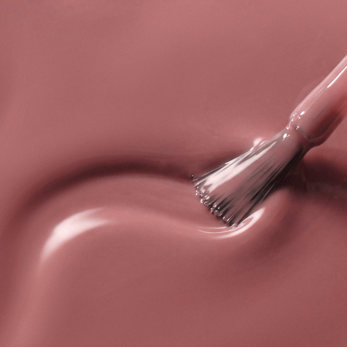 A close-up of a glossy mauve-pink liquid swatch with a brush stroke applying the color.