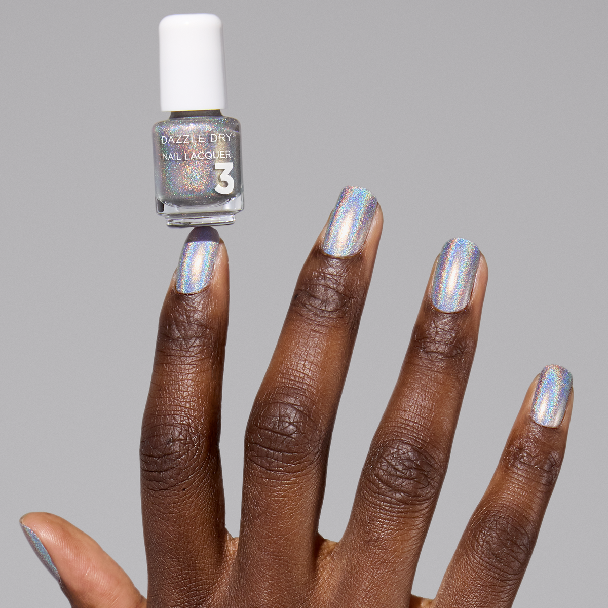 Nail polish bottle with a hand showing nails painted with a metallic silver color on a gray background