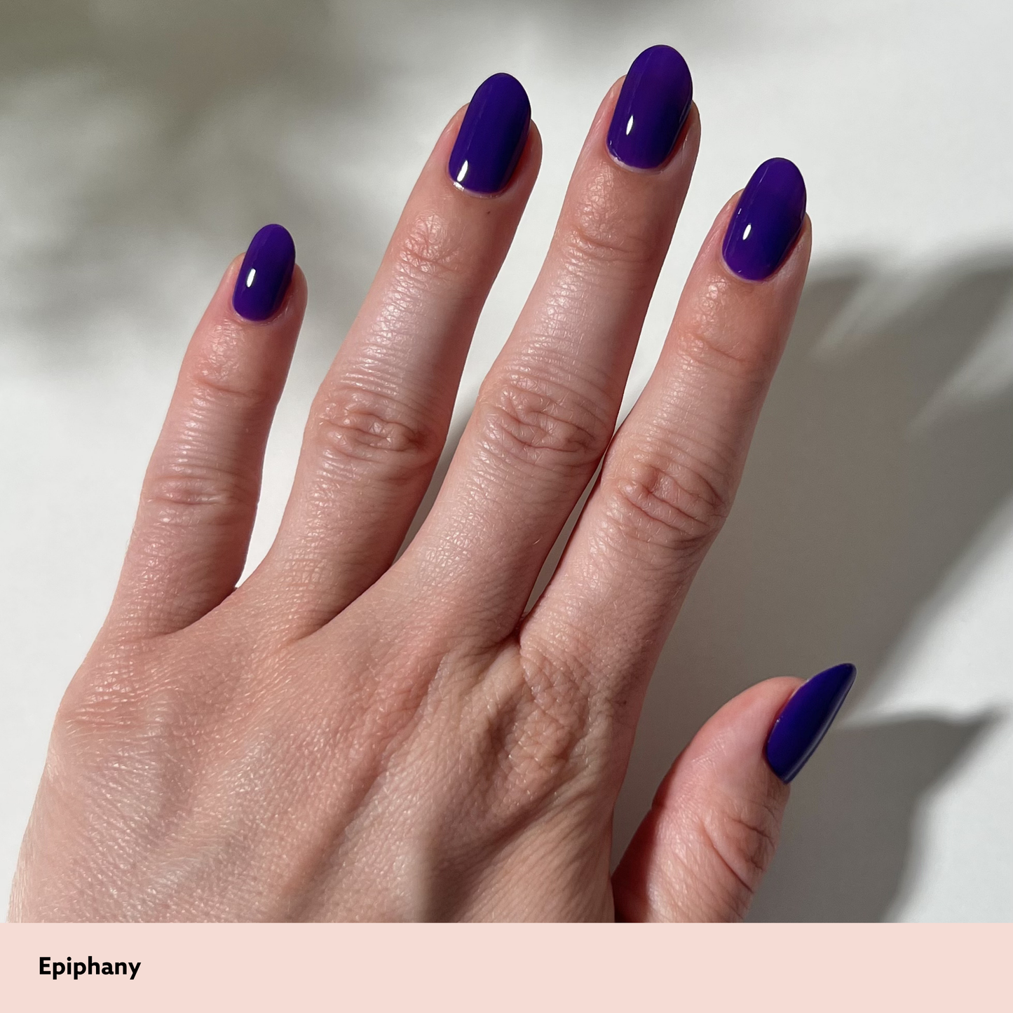 Hand with purple nail polish on a neutral background