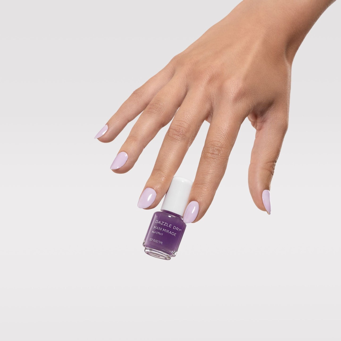Hand holding a bottle of purple nail polish against a light gray background