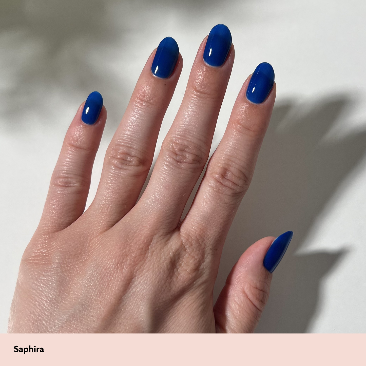 Hand with blue nail polish on a neutral background
