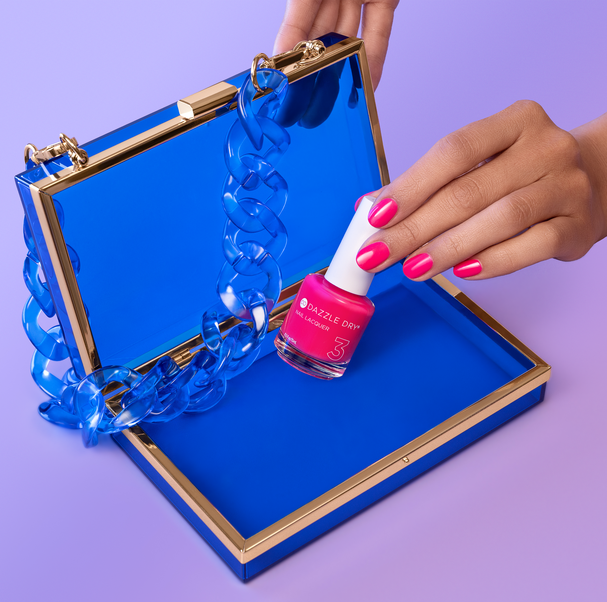 Hand with She's Electric painted on nails holding lacquer bottle inside blue purse.