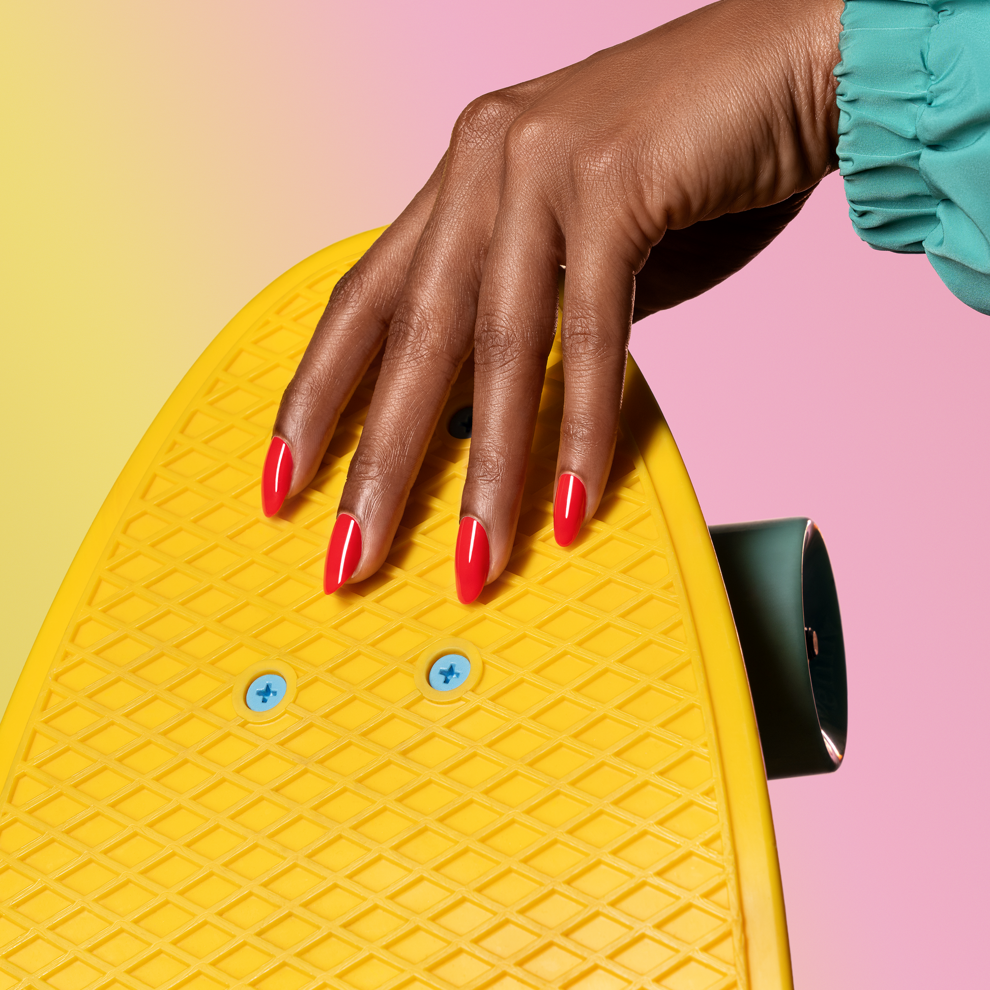 Hand with Spark painted on nails holding a yellow penny board.