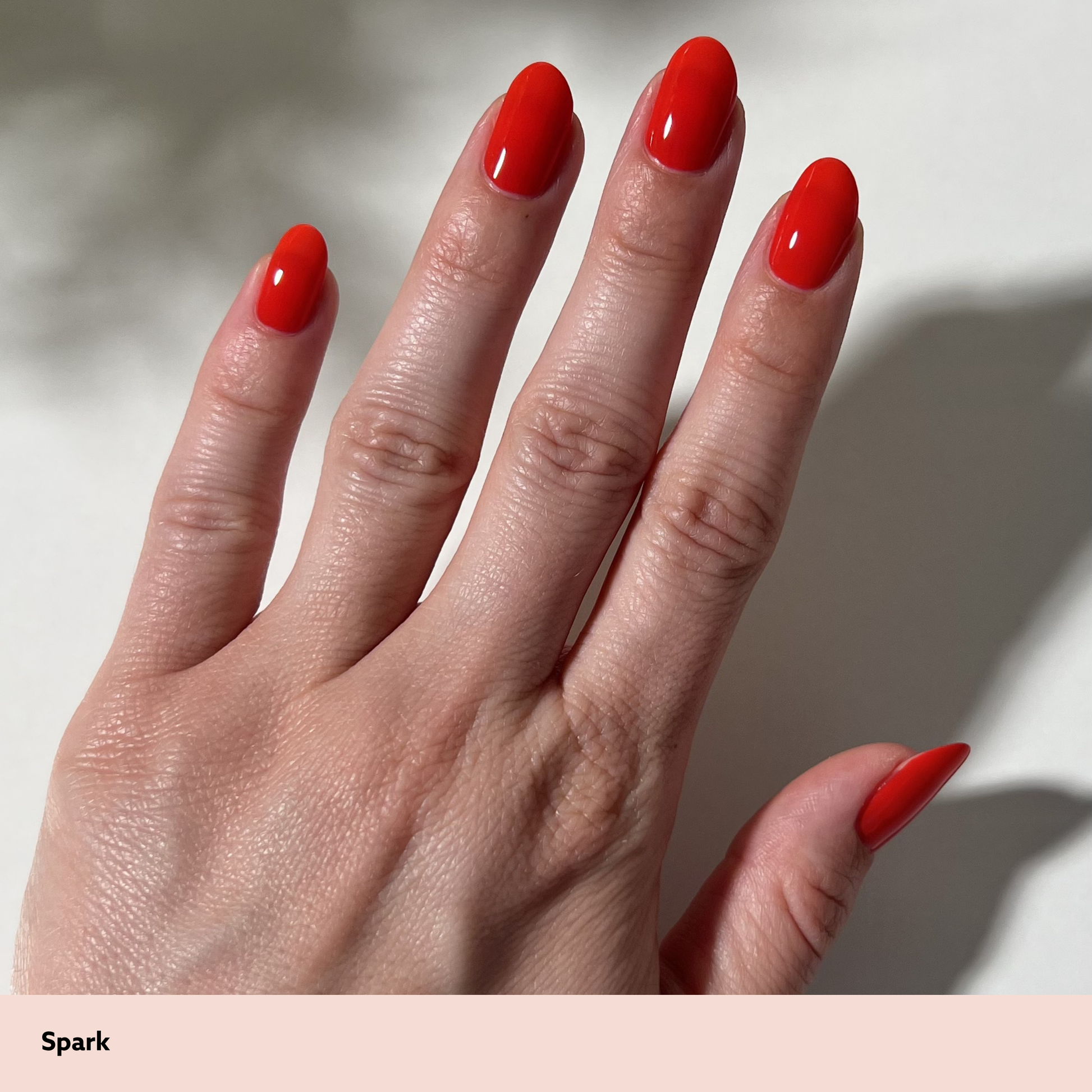 Hand with red nail polish on a neutral background
