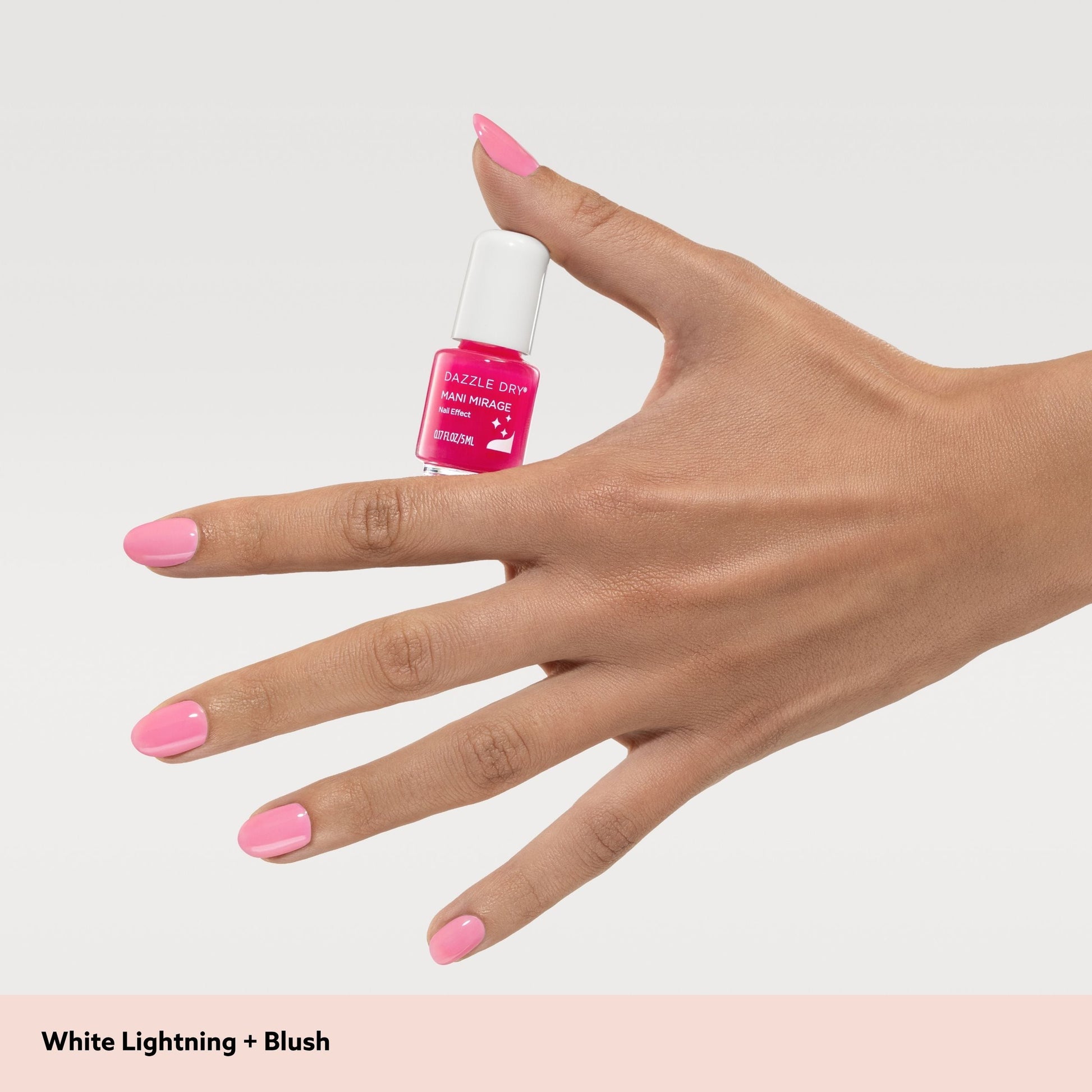 Hand with pink nail polish holding a bottle of nail polish labeled 'White Lightning + Blush'.