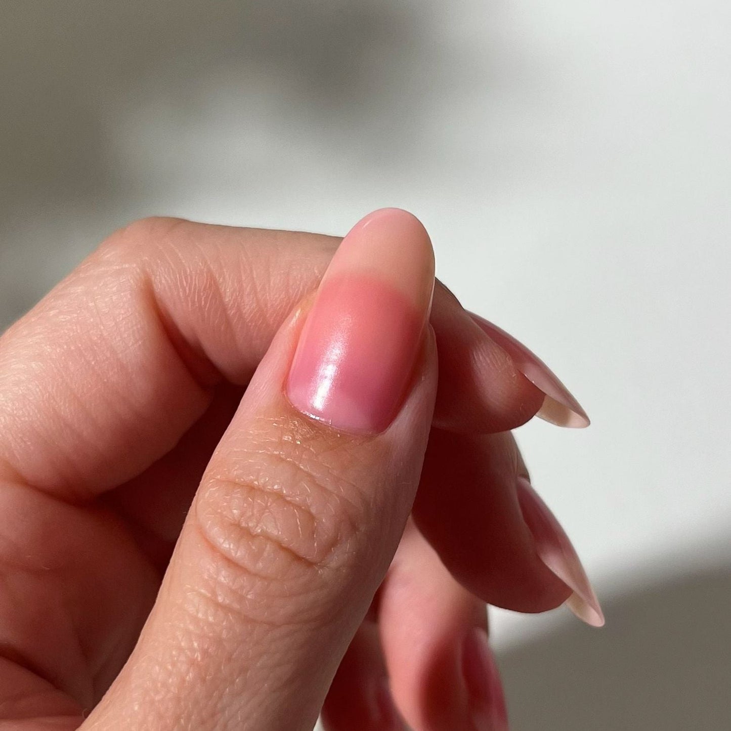 Close-up of a hand with pink nail polish on a blurred background