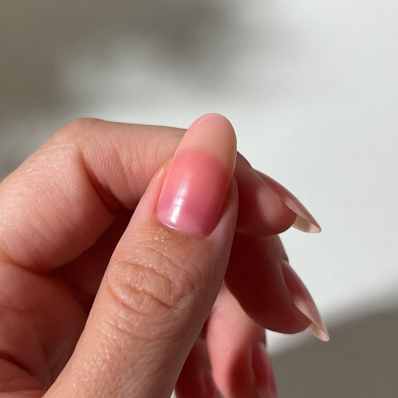 Close-up of a hand with pink nail polish on a blurred background