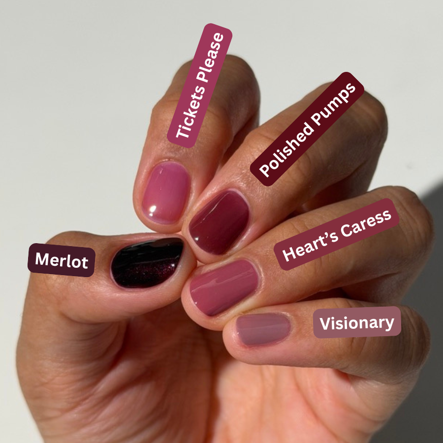 A hand showing six different nail polish colors with custom labels: Merlot, Tickets Please, Polished Pumps, Heart's Caress, Visionary, and a very dark plum. The background is a clean white studio setting.